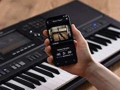 Yamaha Arrange Workstation PSR-SX920 and a hand holding a smartphone with a music player screen