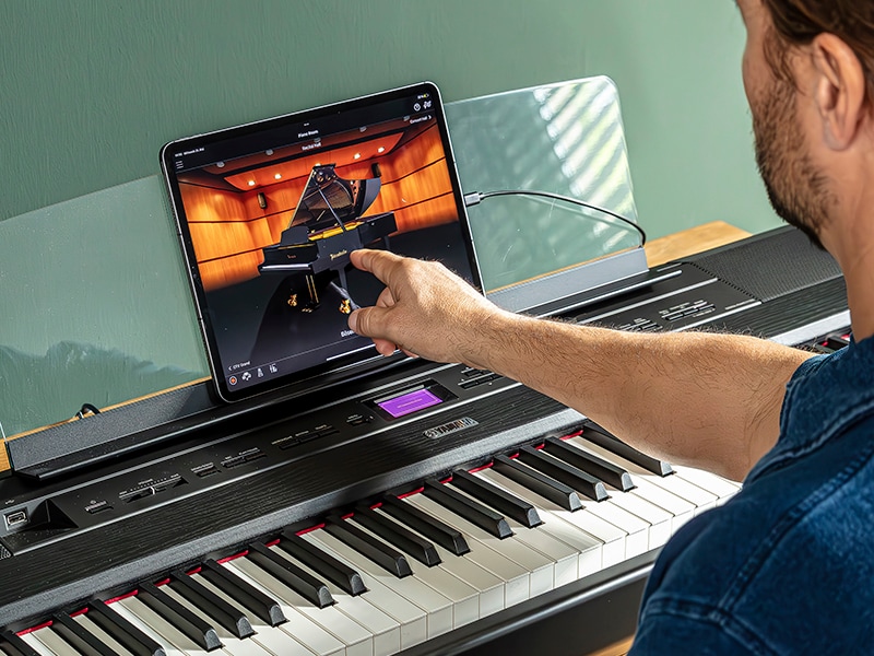 The Yamaha “Smart Pianist” app icon, together with a tablet placed on the music stand of the P-525