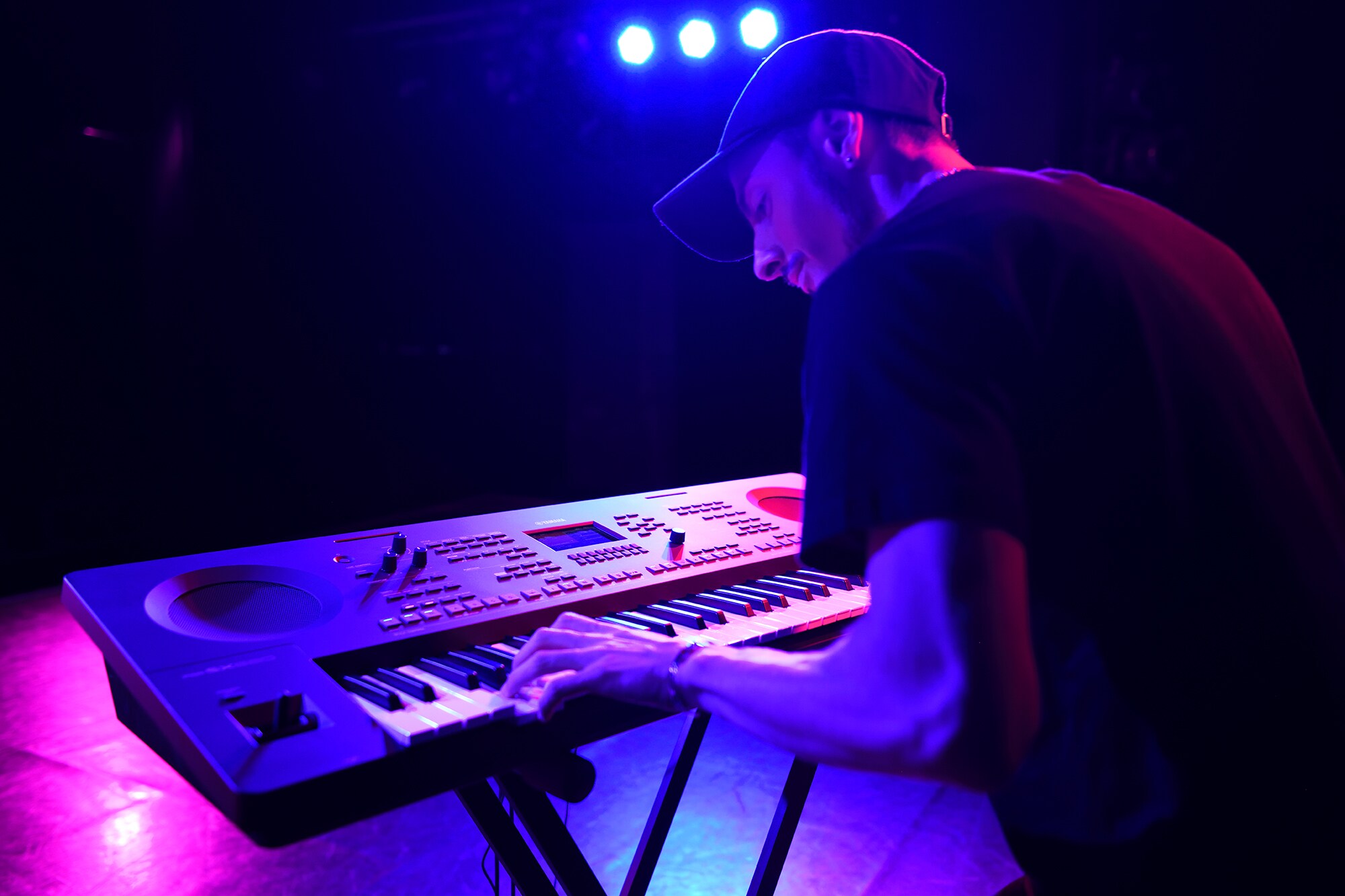 Une personne jouant sur un clavier arrangeur Yamaha installé sur un stand sous les projecteurs de scène
