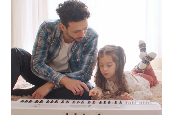 Daughter playing the EZ-310 and father watching on the floor