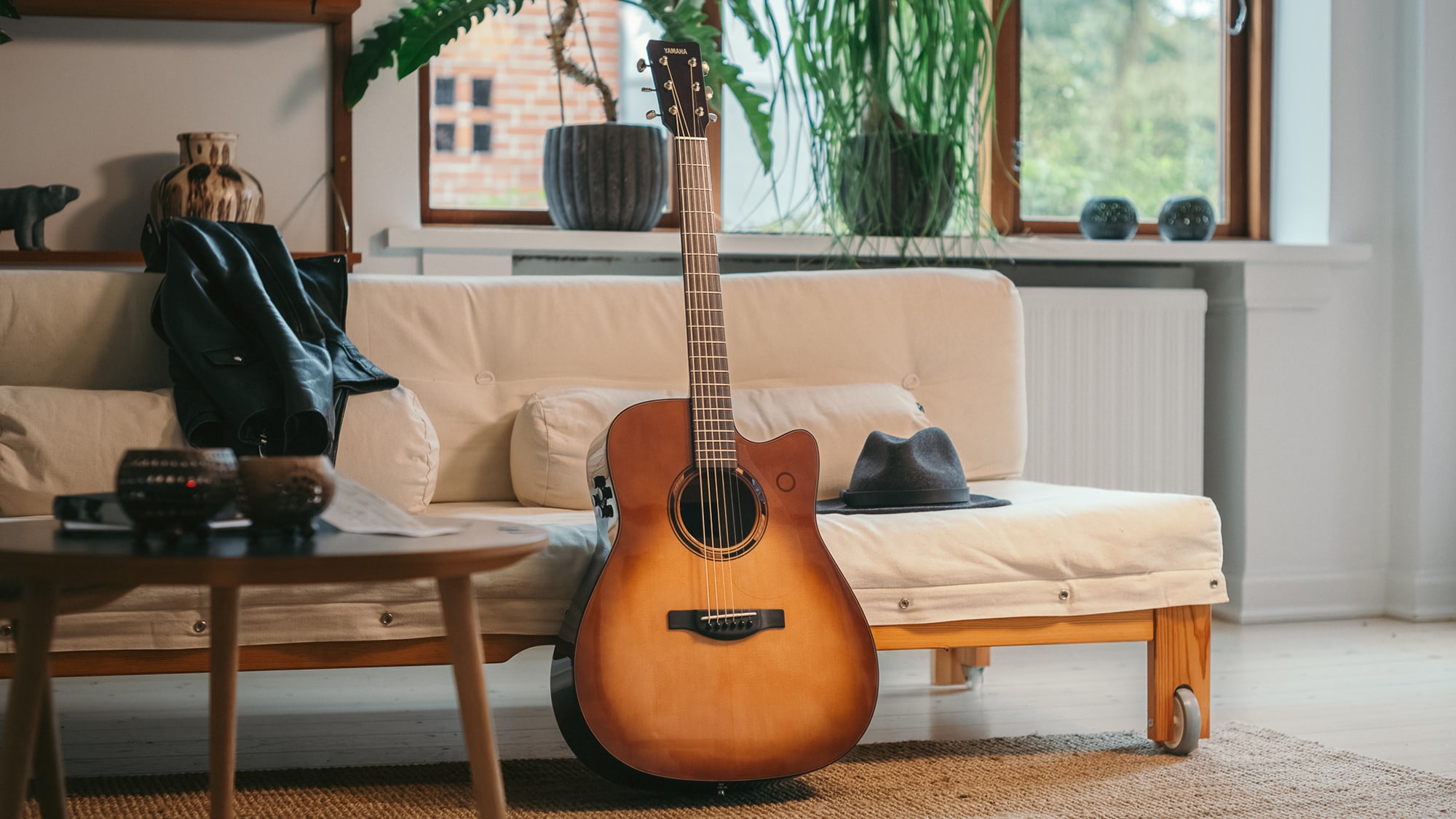 TAG3 C acoustic guitar placed on a sofa with a bag beside it.