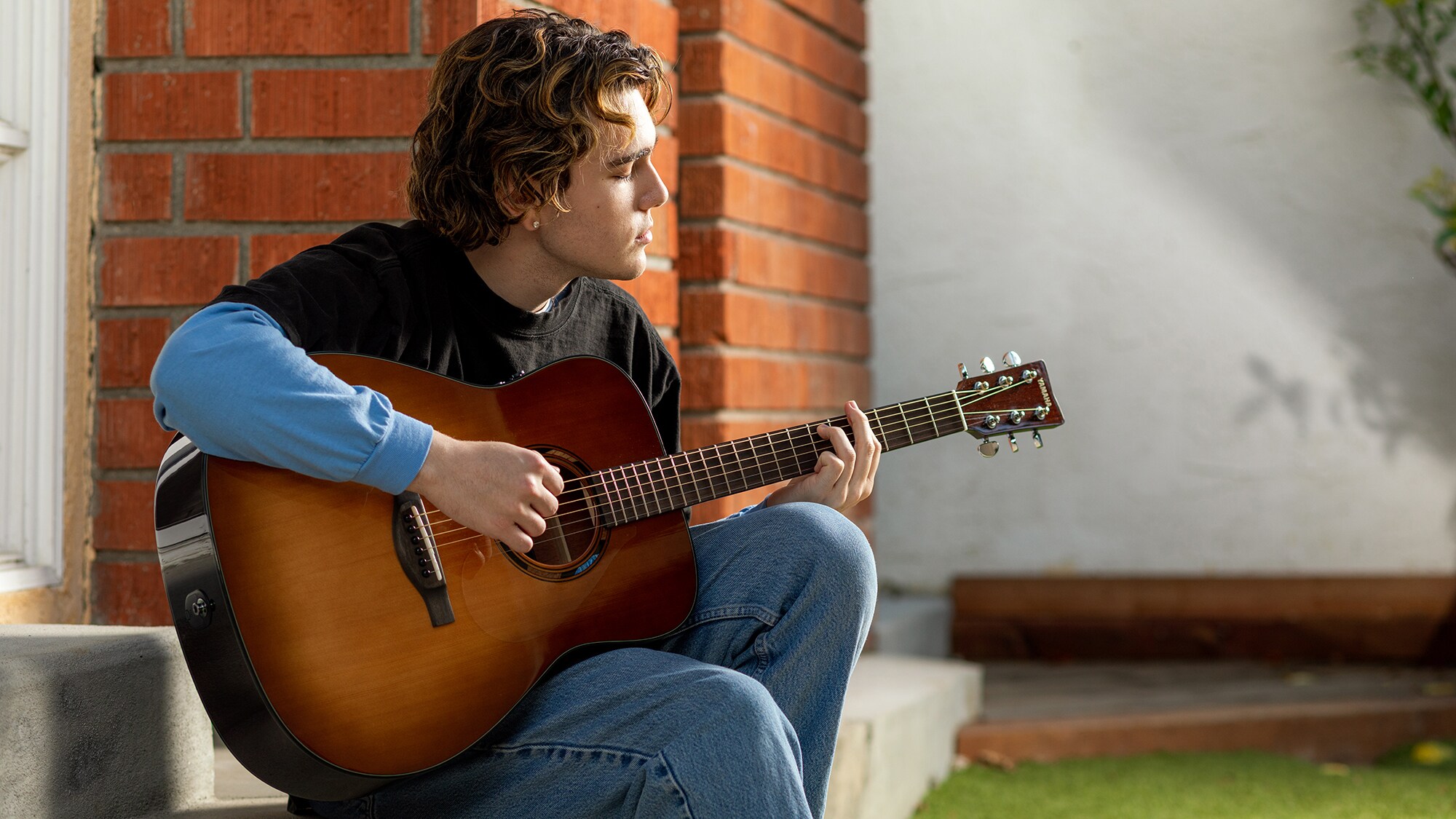 Un homme jouant d'une guitare acoustique TAG1 E à l'extérieur