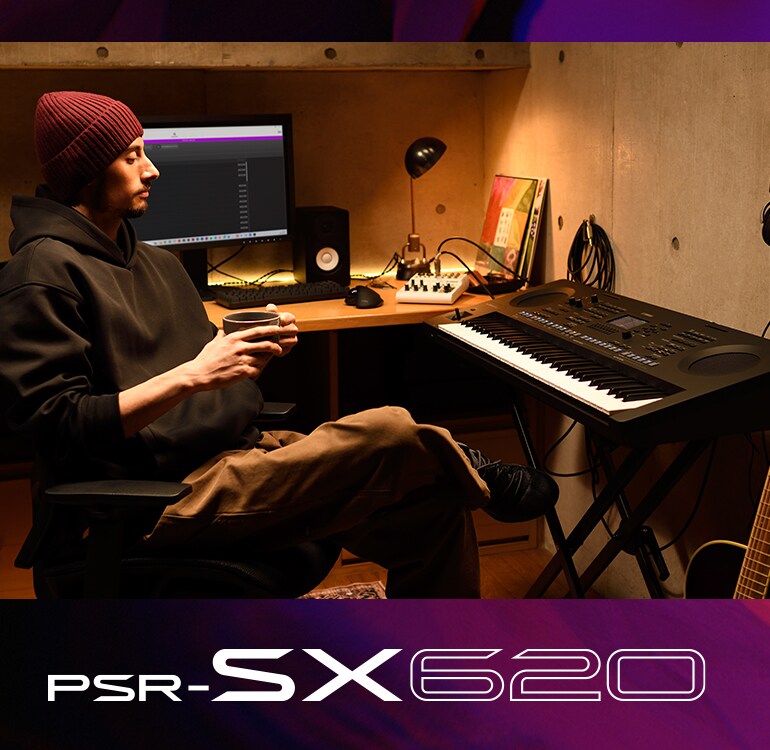 Une personne assise devant un clavier PSR-SX dans un home studio, buvant un café.
