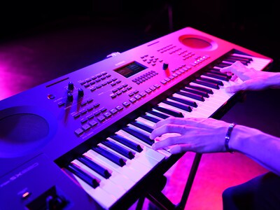 Gros plan sur des mains jouant sur un clavier lors d'une prestation en direct.
