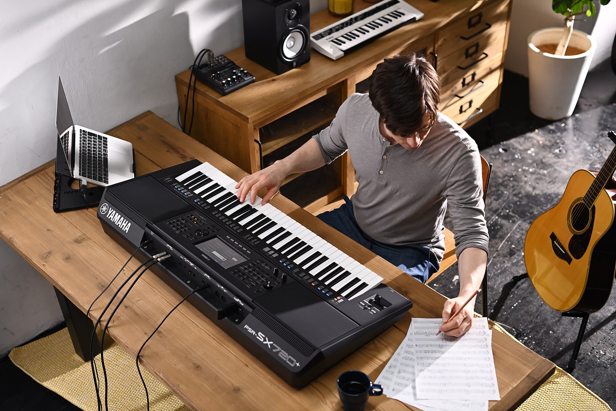 Photo d'une personne écrivant sur une partition tout en jouant sur le clavier arrangeur Yamaha PSR-SX720+