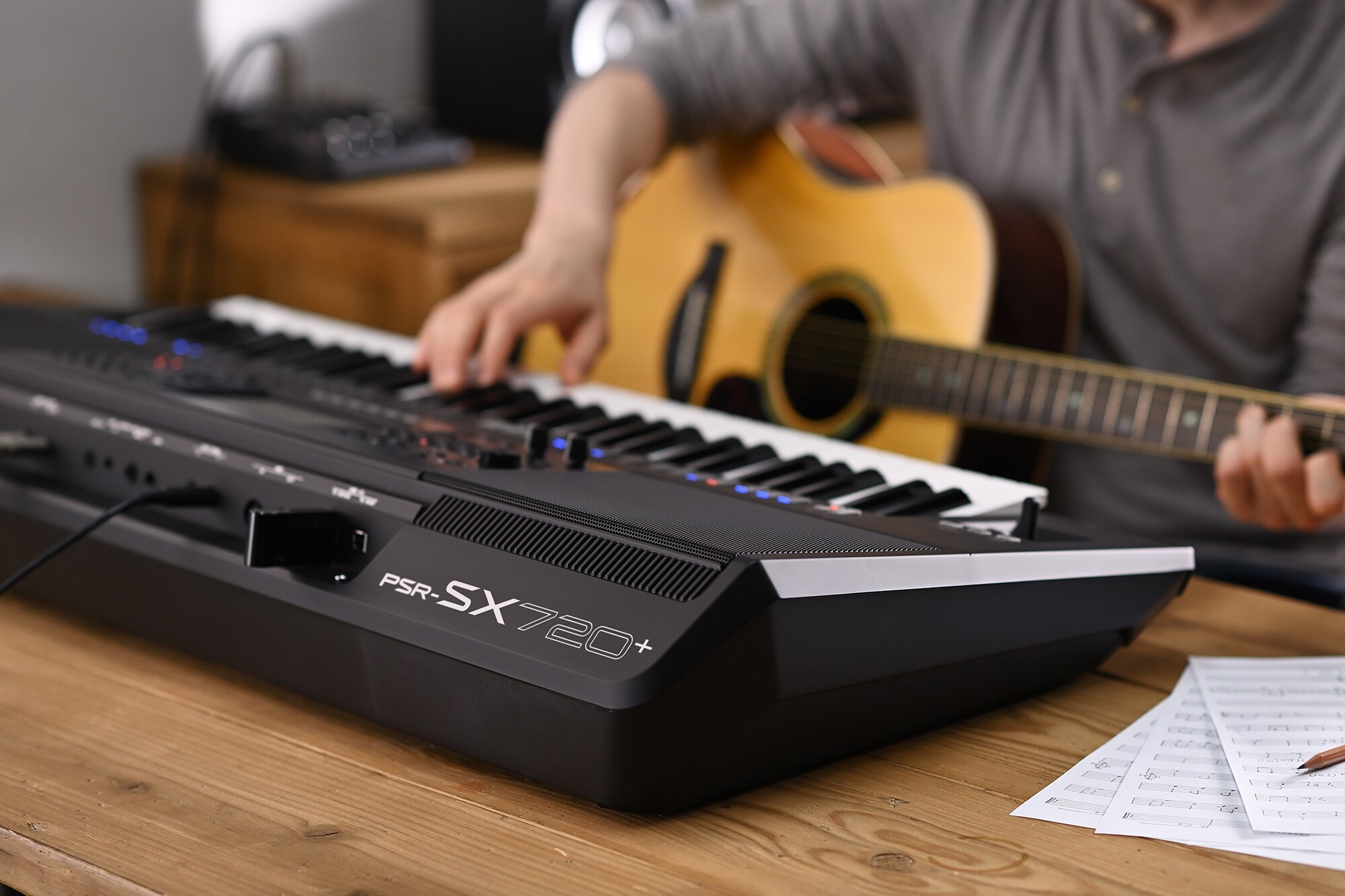 Photo d'une personne jouant sur le clavier arrangeur Yamaha PSR-SX720+ tout en tenant une guitare