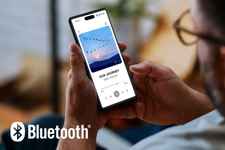 Le logo Bluetooth et un homme utilisant un smartphone pour la lecture de musique.