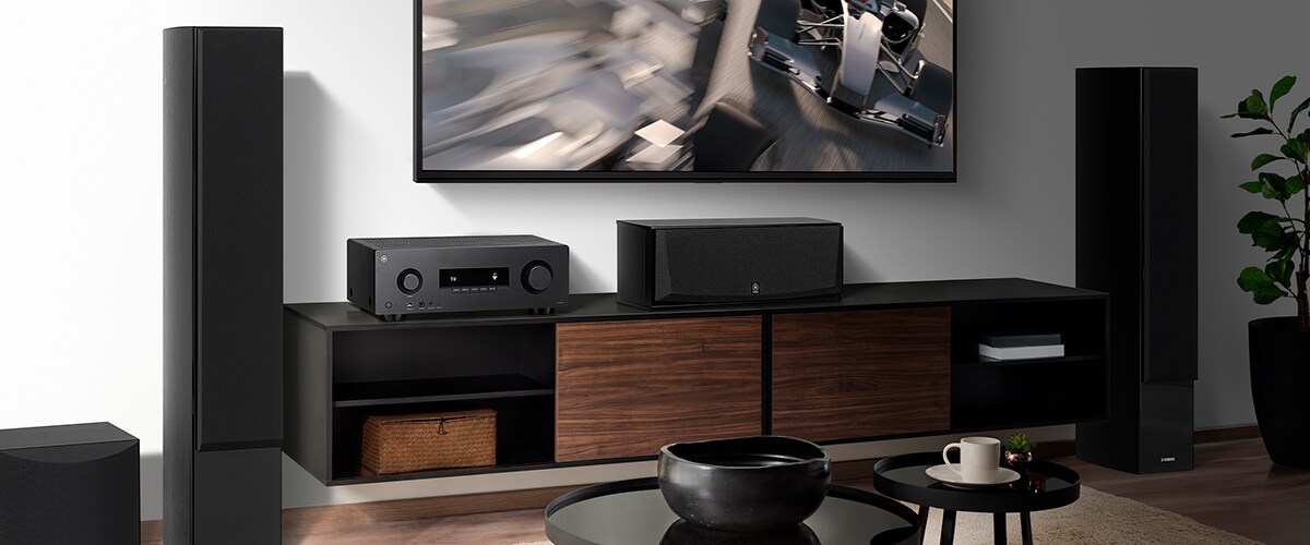 Le RX300A, une enceinte centrale, des enceintes avant et un caisson de basses dans une pièce.