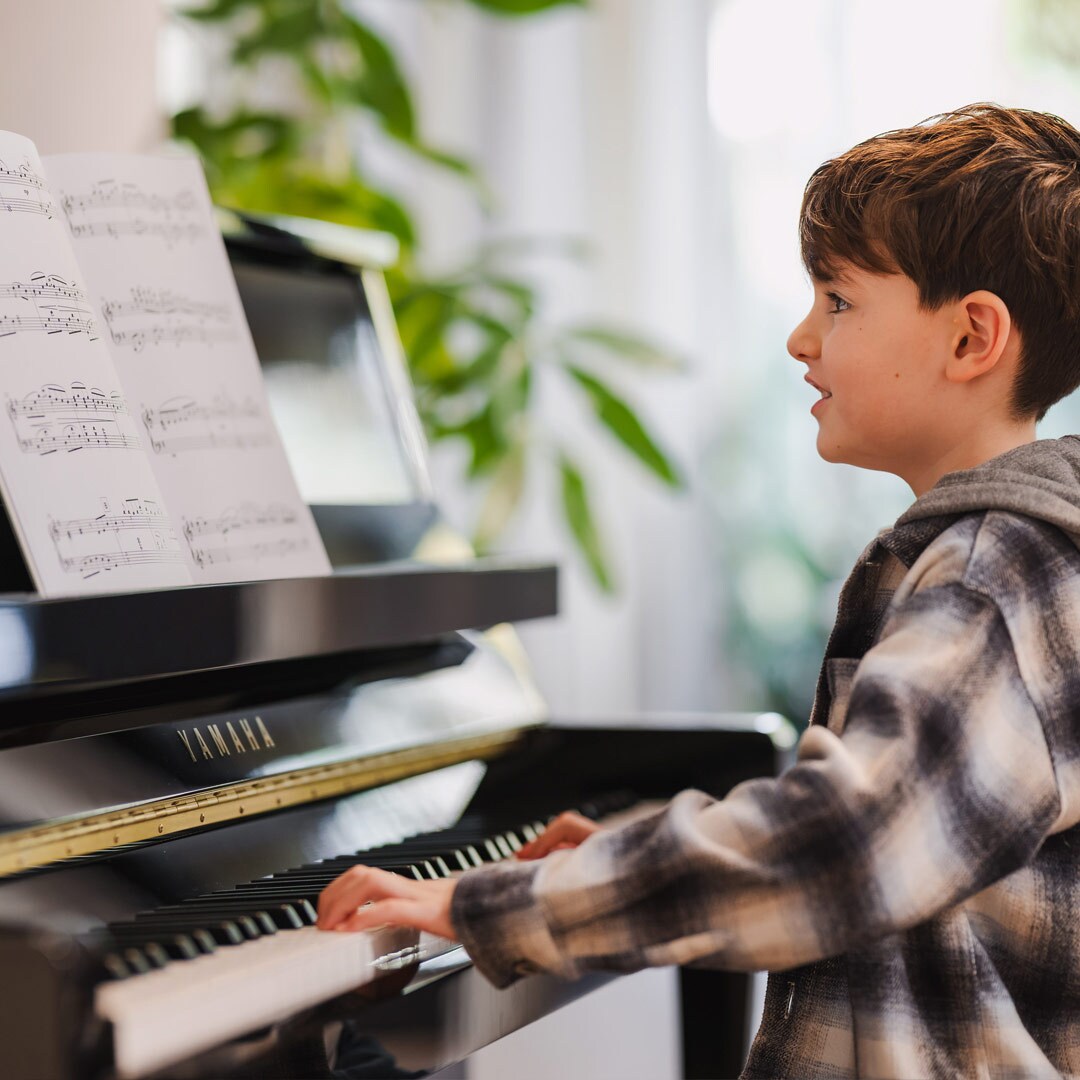 Un enfant apprécie de jouer sur le piano droit de la série B