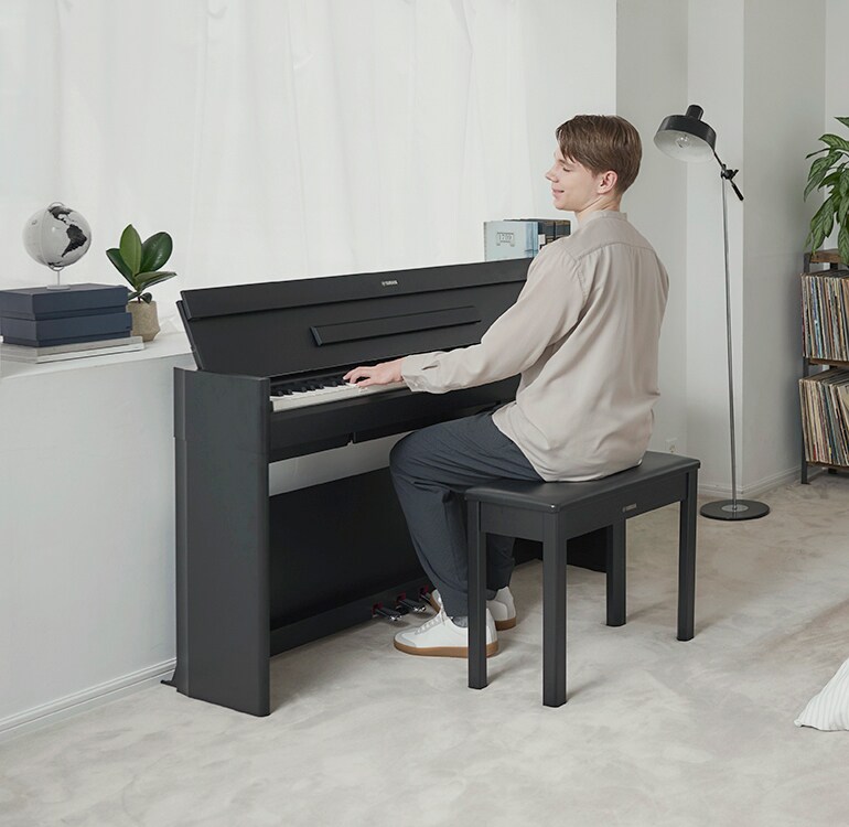 Un homme jouant sur un piano ARIUS dans une chambre, dans une ambiance décontractée