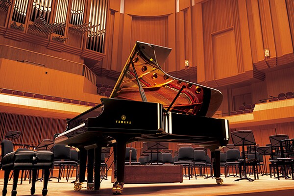 Piano à queue de concert Yamaha CFX sur la scène d'une salle de concert.