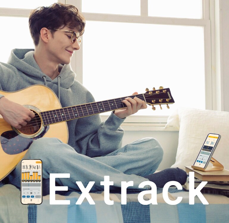 Homme, assis sur un canapé et accompagné de l'application d'entraînement musical Extrack, prenant plaisir à la pratique de la guitare